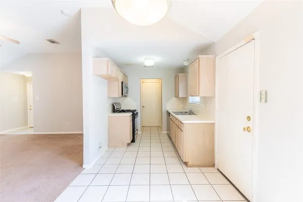 a kitchen with a sink a stove top oven and white cabinets