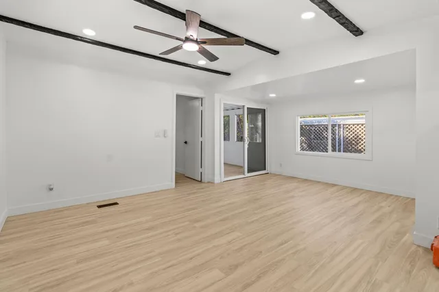 a view of an empty room with a window and wooden floor