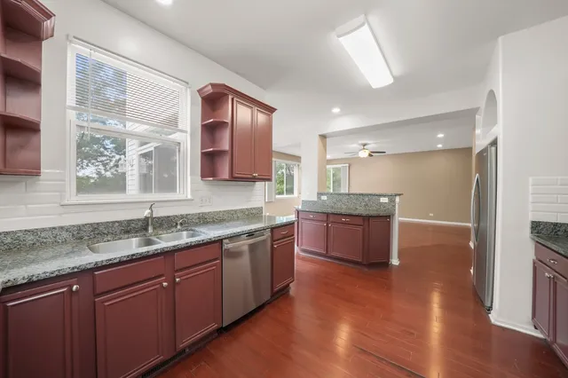 a large kitchen with stainless steel appliances granite countertop a stove a sink and a granite countertops with wooden floor