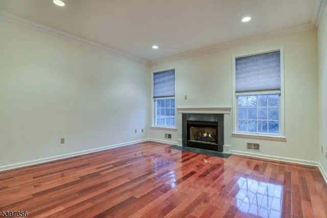 a view of an empty room with wooden floor fireplace and a window