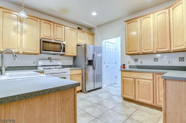 a view of kitchen with stainless steel appliances kitchen island granite countertop dining table chair and a refrigerator