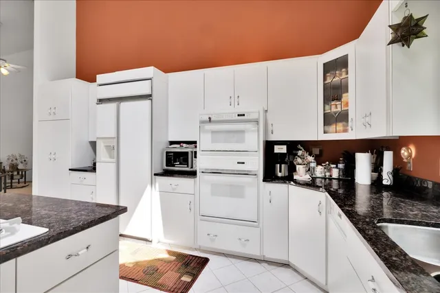a kitchen with granite countertop white cabinets and stainless steel appliances