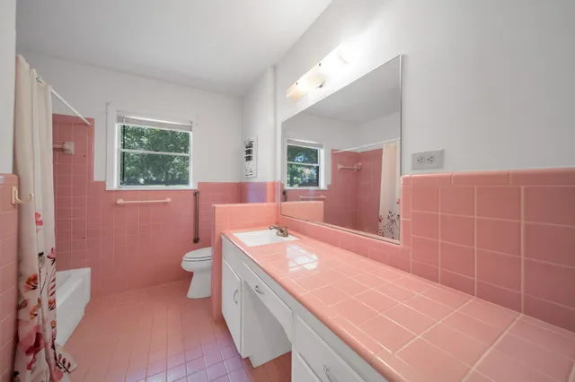 a bathroom with a granite countertop bathtub sink vanity mirror and toilet