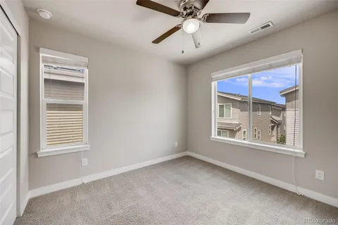 an empty room with windows and fan
