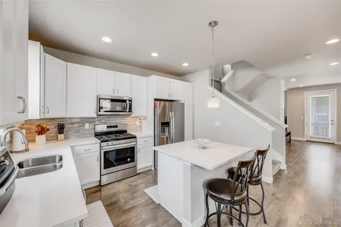 a kitchen with a dining table chairs wooden floor and stainless steel appliances
