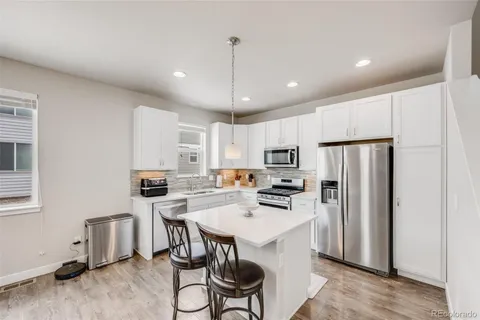 a kitchen with stainless steel appliances a stove a refrigerator a sink a stove a table and chairs