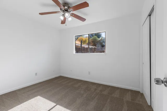 an empty room with a window and a fan