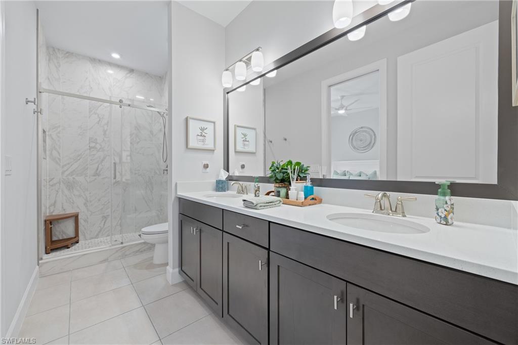 15214 Tolmino Street Naples, FL 34114 - Photo 19 of 47 a bathroom with a double vanity sink toilet and shower