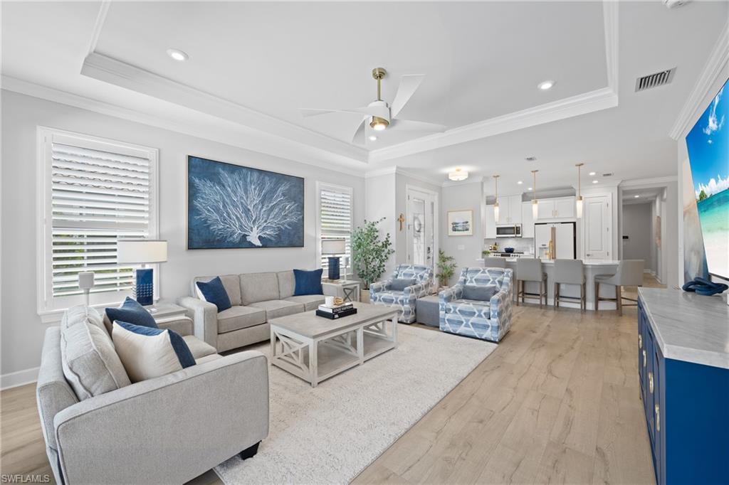 15214 Tolmino Street Naples, FL 34114 - Photo 2 of 47 a living room with furniture and a chandelier