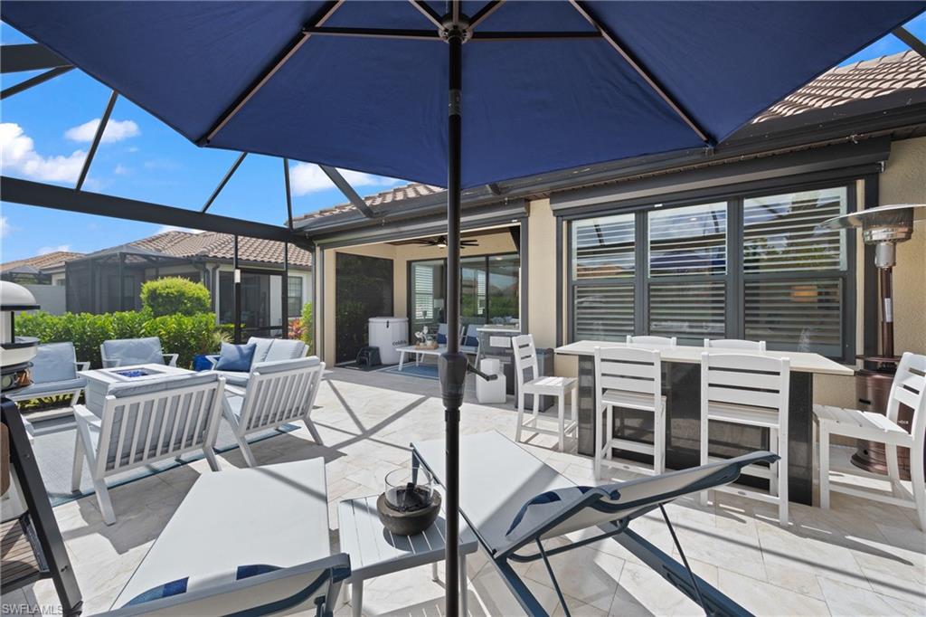 15214 Tolmino Street Naples, FL 34114 - Photo 28 of 47 a view of a patio with a table and chairs under an umbrella