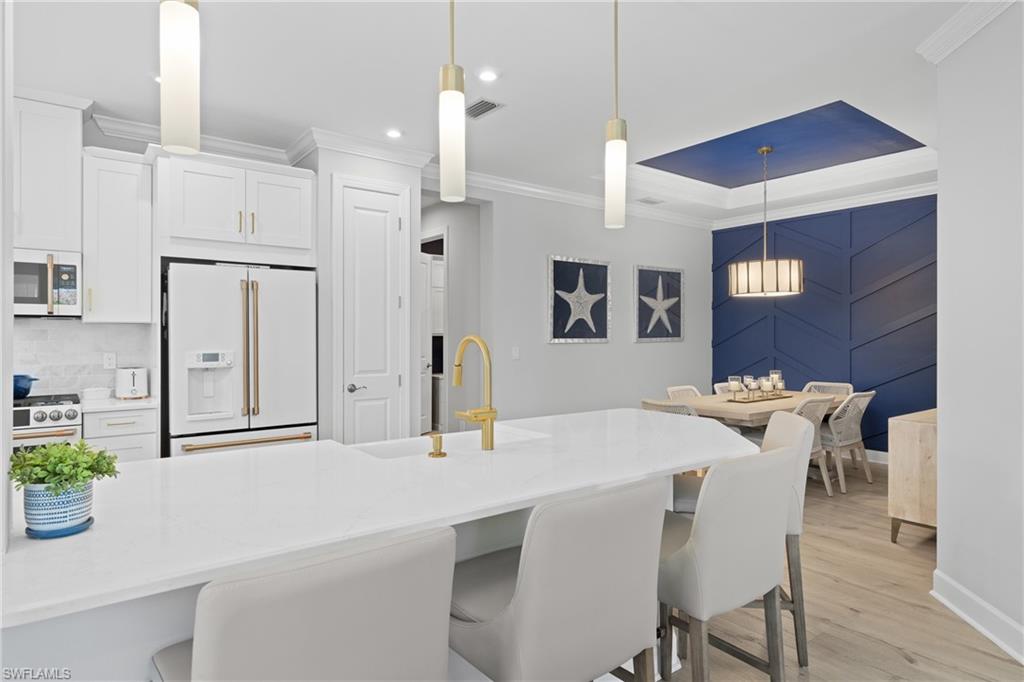 15214 Tolmino Street Naples, FL 34114 - Photo 5 of 47 a kitchen with stainless steel appliances kitchen island granite countertop a table chairs and a refrigerator