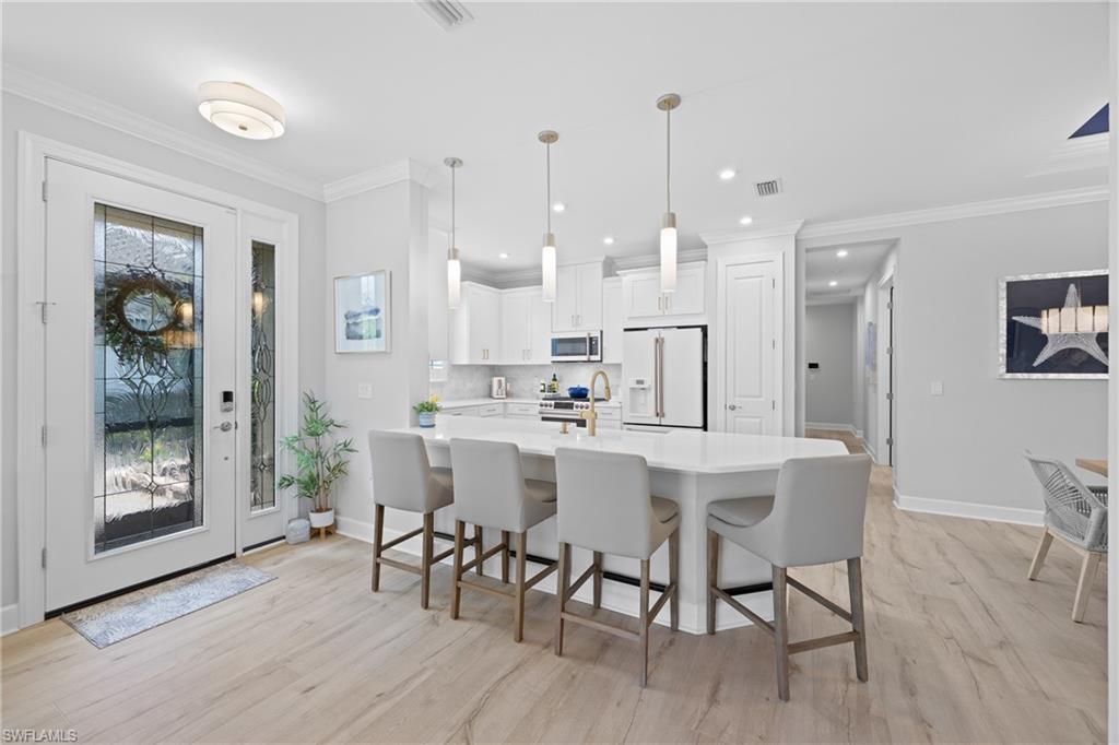 15214 Tolmino Street Naples, FL 34114 - Photo 6 of 47 a dining room with stainless steel appliances kitchen island granite countertop a table chairs and a refrigerator