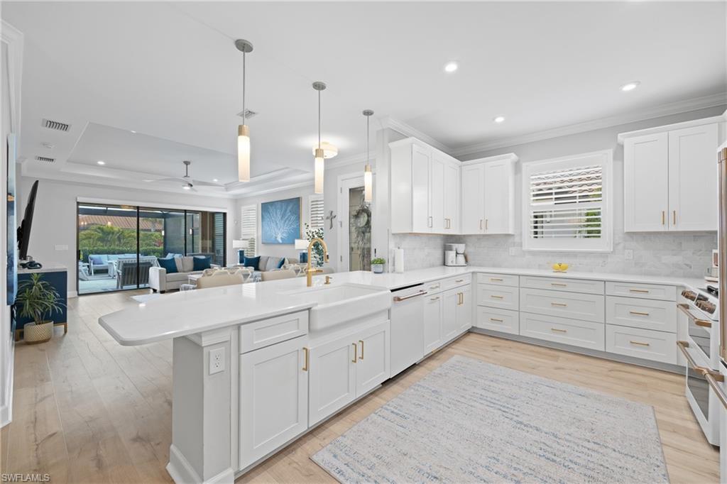15214 Tolmino Street Naples, FL 34114 - Photo 7 of 47 a large white kitchen with kitchen island white cabinets and a sink
