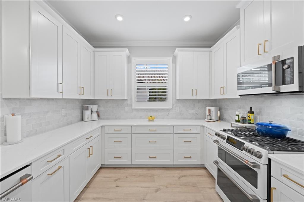 15214 Tolmino Street Naples, FL 34114 - Photo 8 of 47 a kitchen with stainless steel appliances granite countertop white cabinets sink and stove