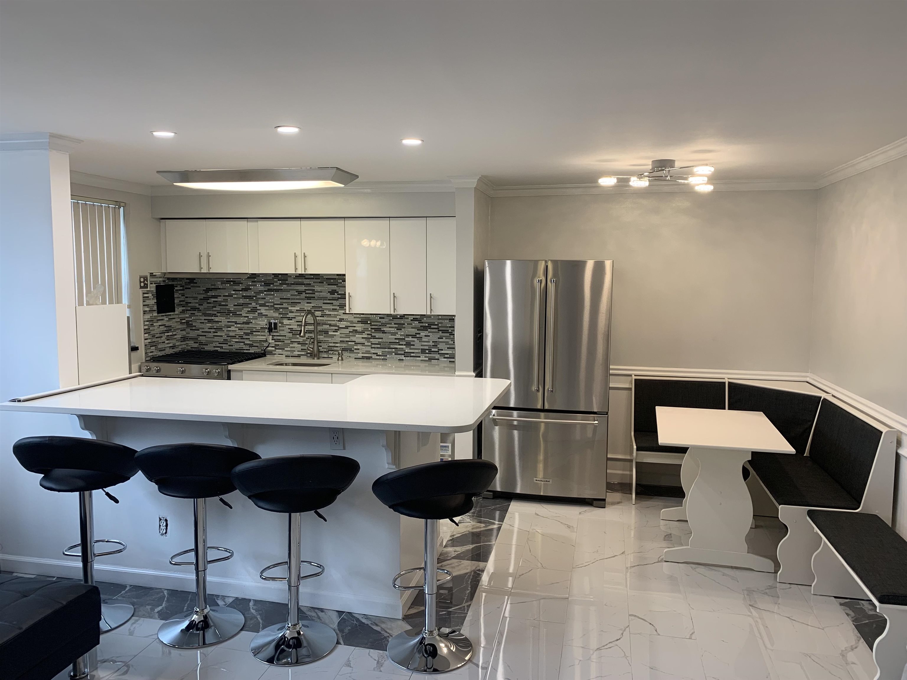 a kitchen with stainless steel appliances kitchen island granite countertop a refrigerator and chairs
