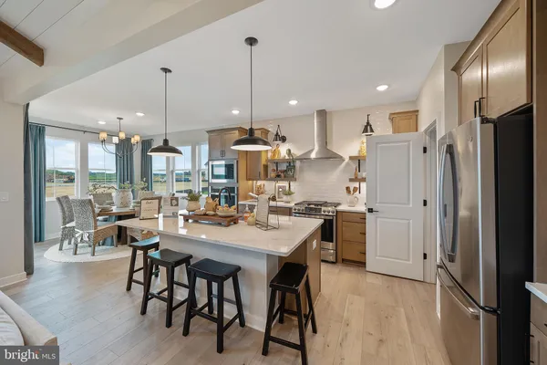 a kitchen with stainless steel appliances kitchen island granite countertop a refrigerator a stove a kitchen island and chairs with wooden floor