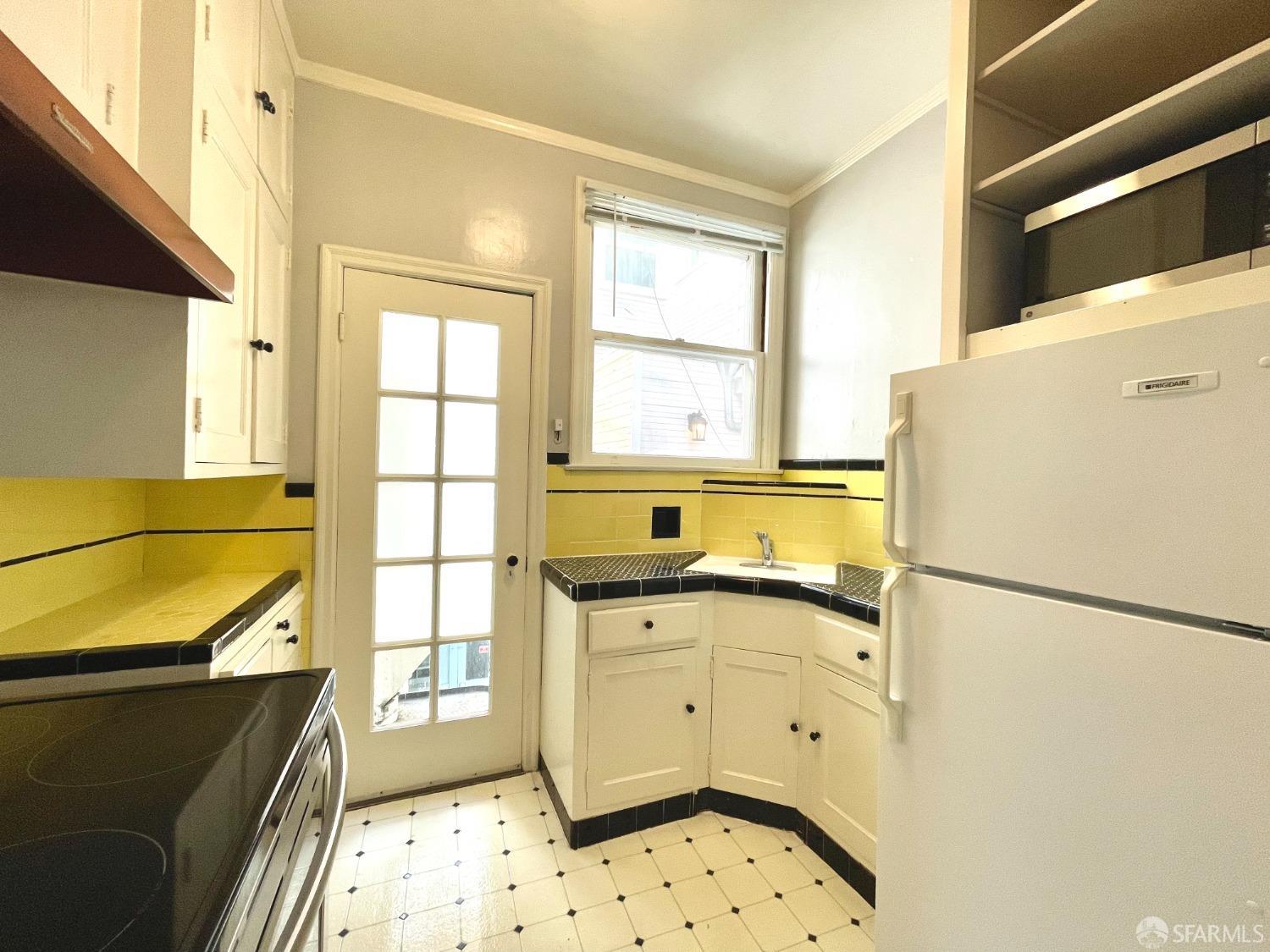 201 Waller Street San Francisco, CA 94102 - Photo 11 of 17 a kitchen with granite countertop a refrigerator a sink and white cabinets