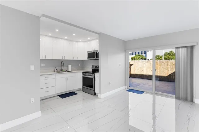 a kitchen with stainless steel appliances granite countertop grey cabinets a stove a sink and a microwave