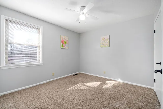 an empty room with a window and a fan