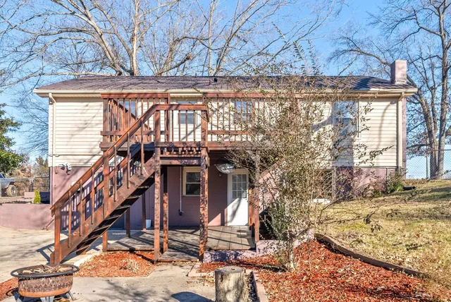 a view of wooden house with large trees and wooden fence
