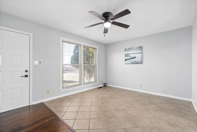 a view of an empty room with a window and wooden floor