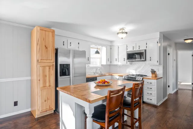 a kitchen with stainless steel appliances a refrigerator a stove a sink a dining table and chairs