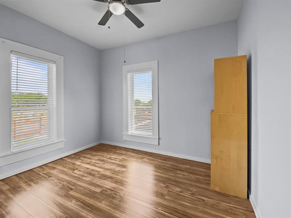 815 Stonecrest Road Argyle, TX 76226 - Photo 10 of 17 Wood-finish flooring, two windows with blinds, ceiling fan, and light blue wall color