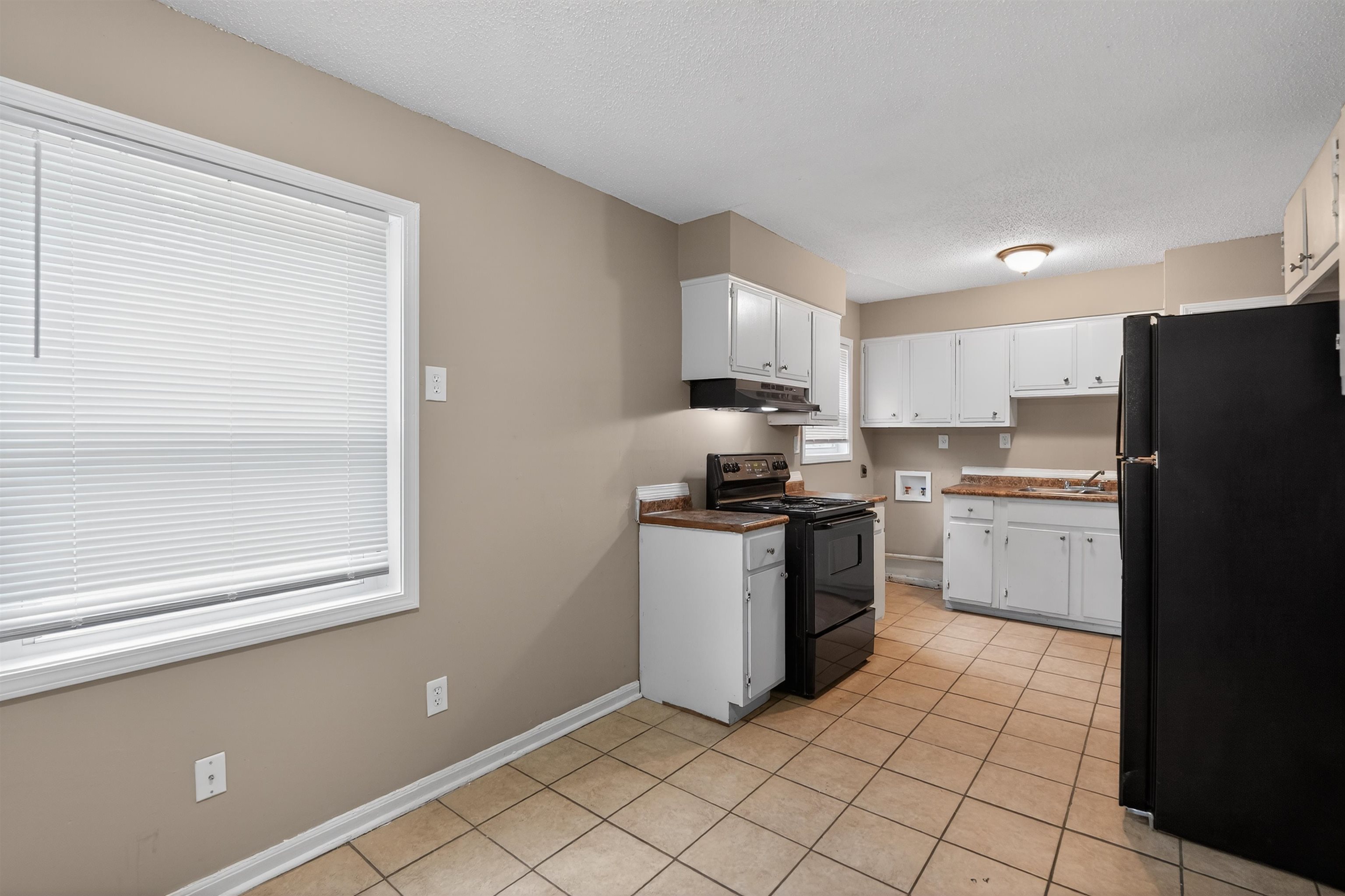 3608 Cane Ridge Drive Memphis, TN 38109 - Photo 18 of 31 Kitchen featuring white cabinetry, wood-finish countertops, black appliances, and neutral tile flooring