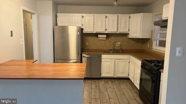 a kitchen with stainless steel appliances granite countertop a refrigerator a stove and white cabinets