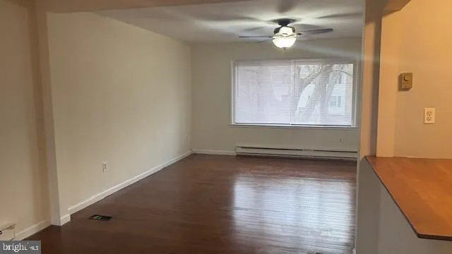 an empty room with wooden floor chandelier fan and windows
