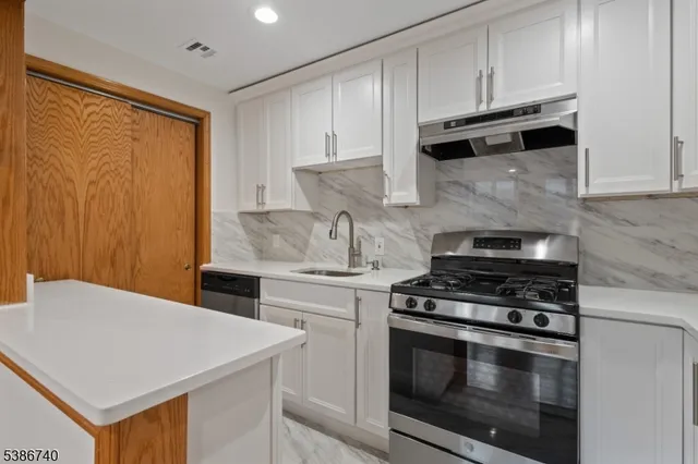 a kitchen with stainless steel appliances a stove a microwave and white cabinets