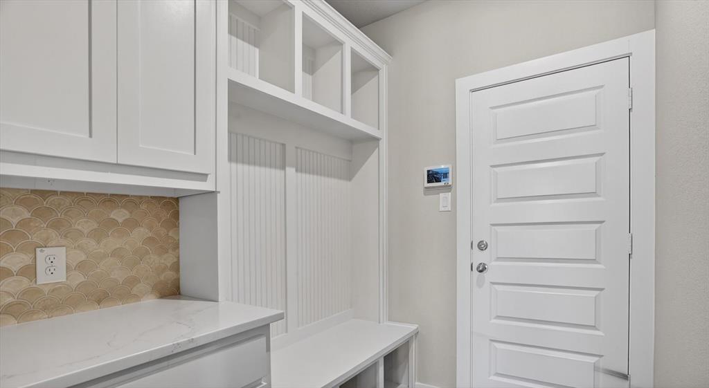 504 Clifton Court Springtown, TX 76082 - Photo 35 of 36 Built-in mudroom organization featuring upper cabinetry, open shelving, beadboard accents, and a bench with cubbies