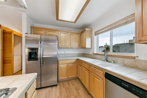 a kitchen with stainless steel appliances granite countertop a sink a stove and a wooden floors
