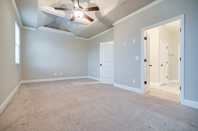 an empty room with chandelier fan and windows