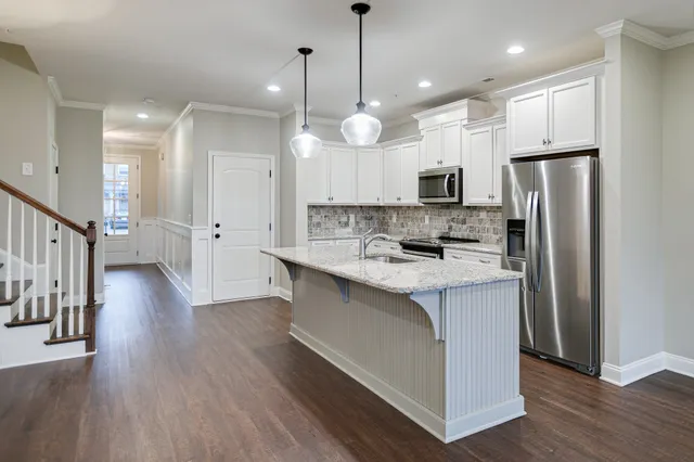 a large kitchen with stainless steel appliances kitchen island a large counter top a sink a refrigerator and a stove