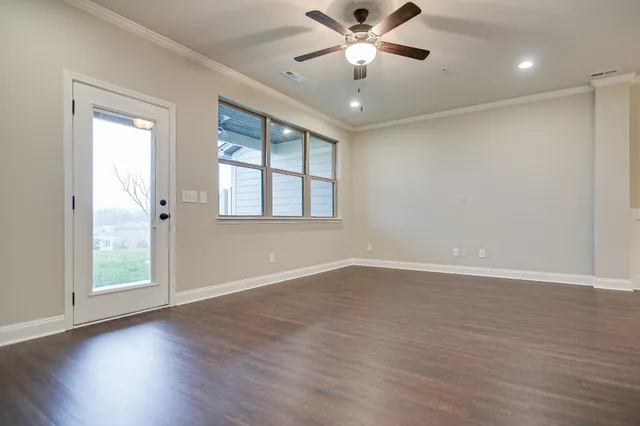 an empty room with wooden floor fan and windows