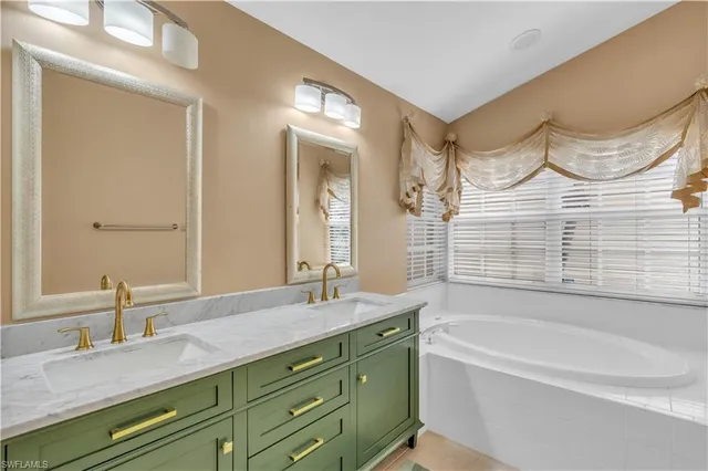 a bathroom with a granite countertop sink mirror and a bathtub