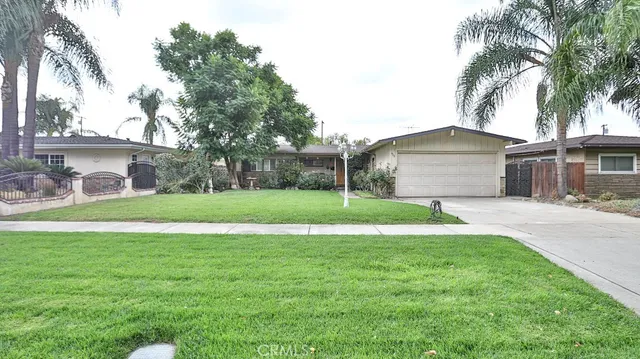 a view of a house with a yard and palm trees
