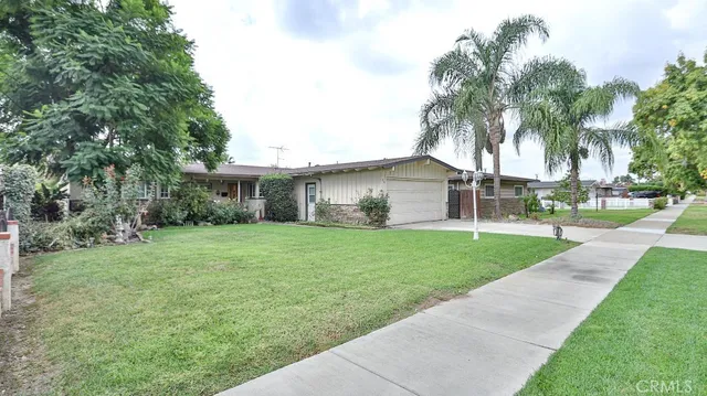 a view of a house with a yard and palm trees