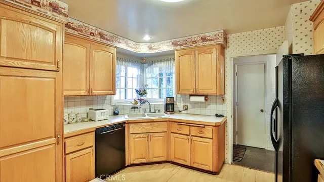 a kitchen with a sink a refrigerator a window and cabinets