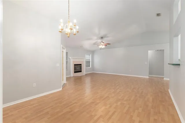 a view of an empty room with chandelier and wooden floor