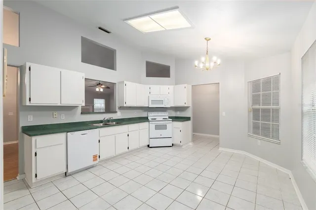 a large white kitchen with cabinets a sink a window and a stainless steel appliances