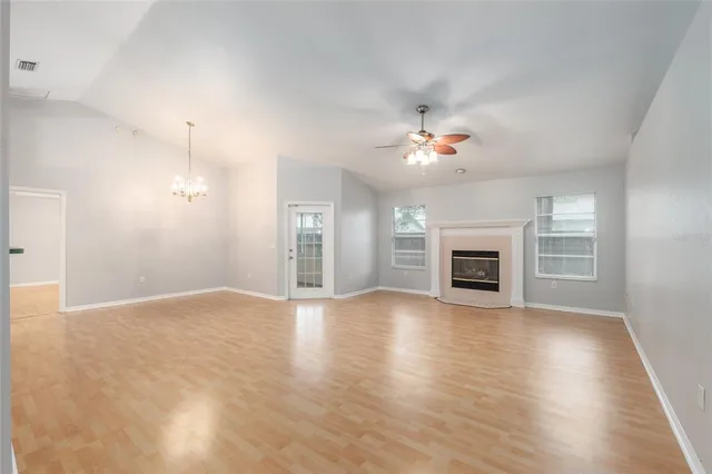 an empty room with wooden floor fireplace and window