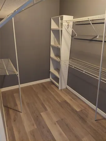 a view of an empty room with wooden floor and white walls
