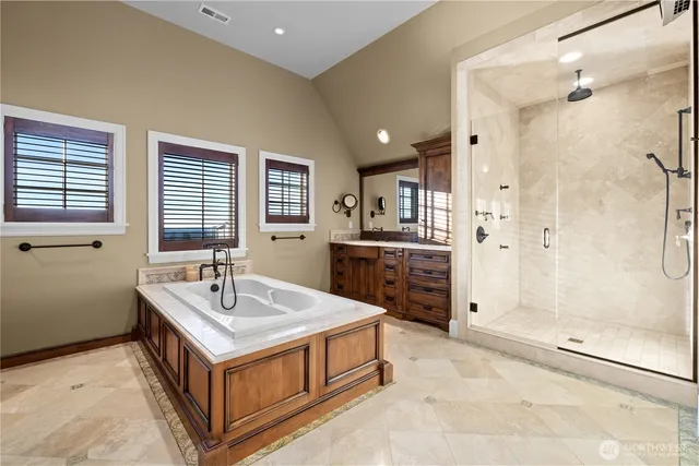 a spacious bathroom with a tub sink shower and mirror