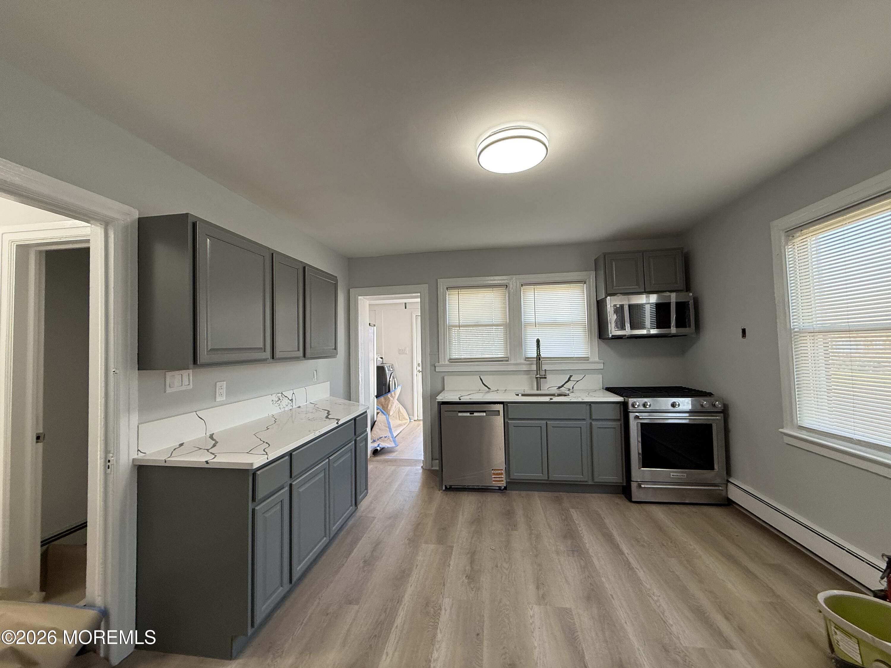 464 2nd Avenue, Unit 1 Long Branch, NJ 07740 - Photo 26 of 37 a large kitchen with granite countertop a stove top oven a sink dishwasher and a refrigerator with wooden floor