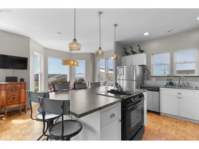 a kitchen with stainless steel appliances granite countertop a stove a sink dishwasher a dining table and chairs with wooden floor