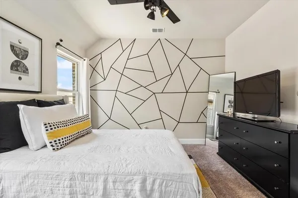 a bedroom with a bed and a flat tv screen on the dresser