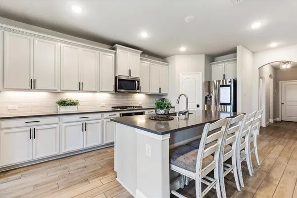 a kitchen with stainless steel appliances granite countertop a stove a sink dishwasher a microwave oven and a white cabinets