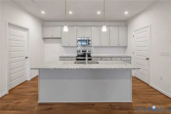 a view of kitchen with stainless steel appliances granite countertop wooden floors and view living room